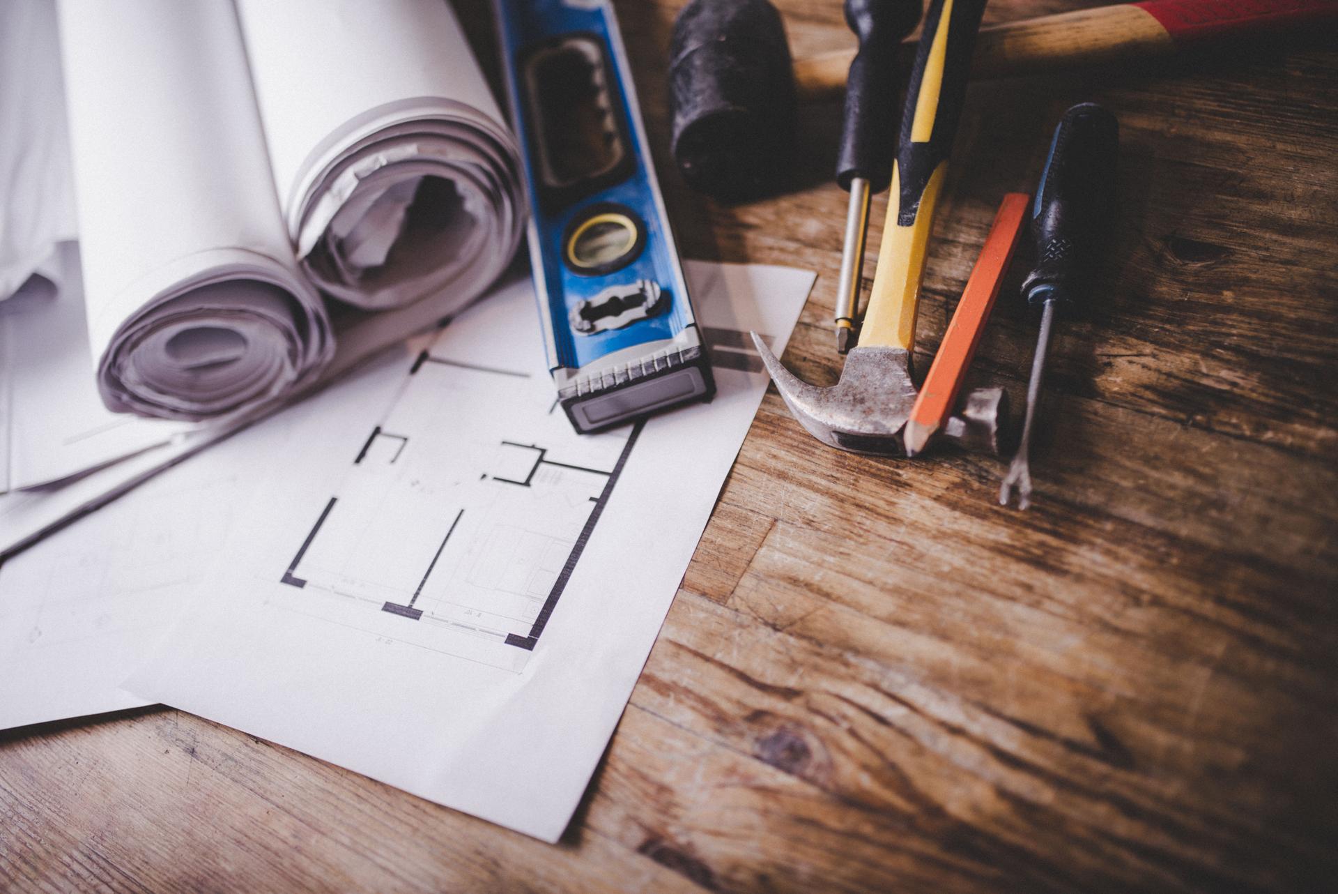 Architectural drawings and construction tools on a wooden desk